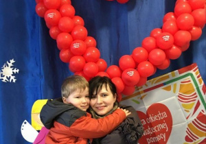 Mama z synkiem na rękach z sercem z balonów w tle